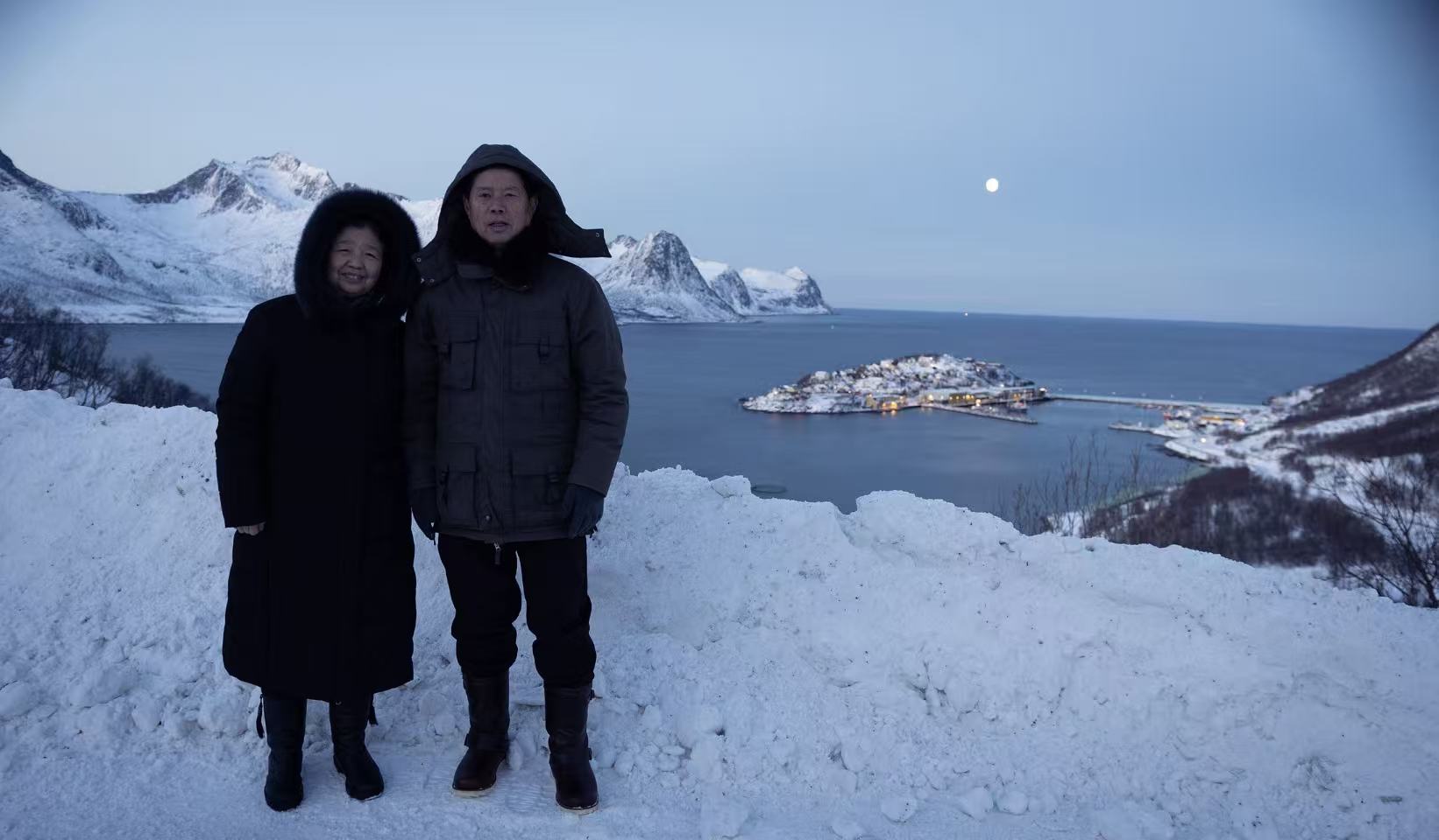 Couple on the shore with snowy peaks behind